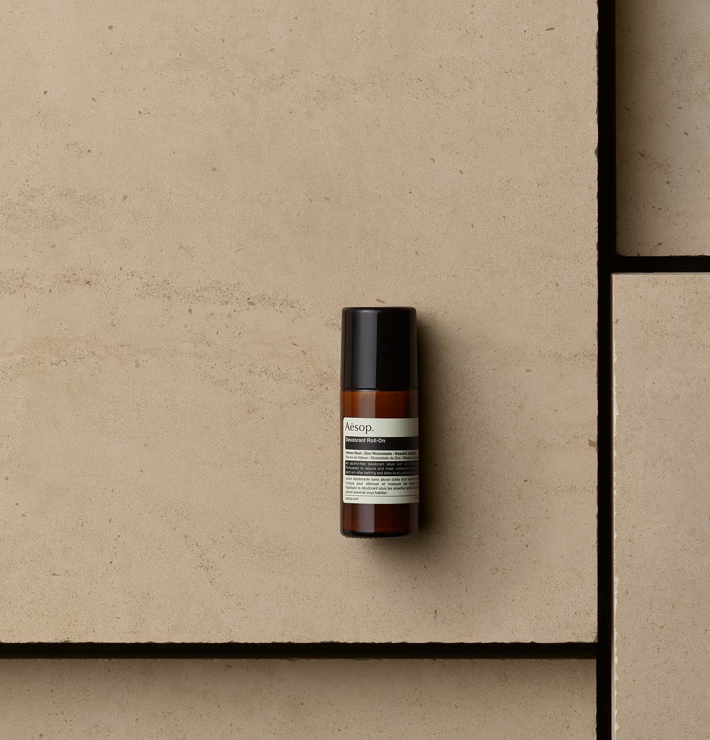 50ml Aesop Deodorant Roll-On bottle resting on a tile