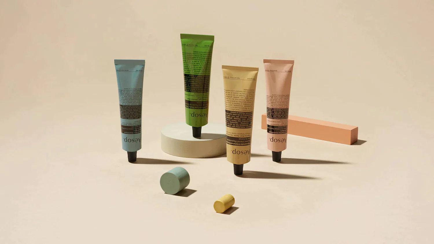 Four tubes of Aesop products displayed with cylinder blocks