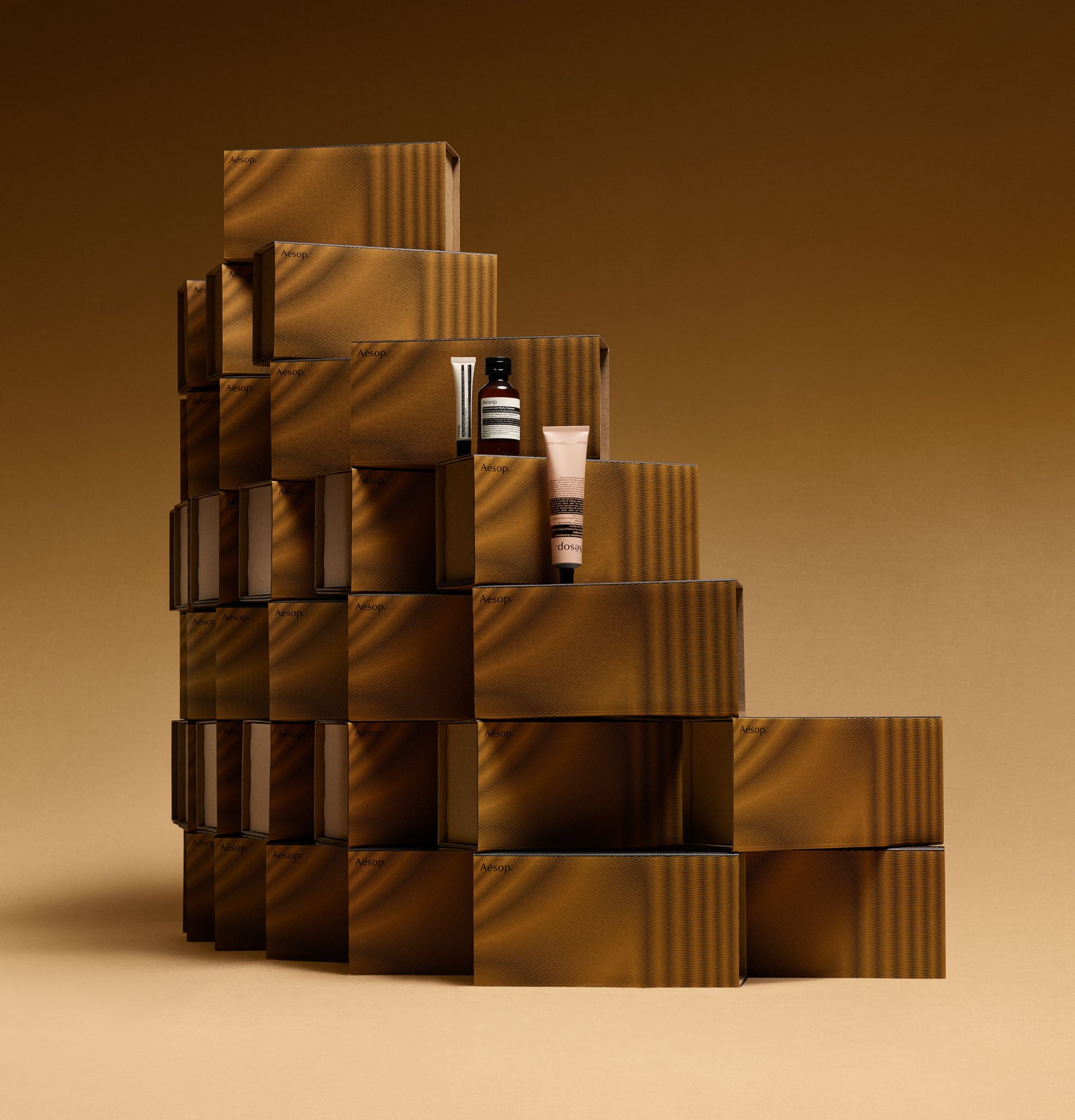 Aesop Resurrection Aromatique hand balm, Geranium Leaf body cleanser, Cedar & Citrus lip salve on a stack of boxes