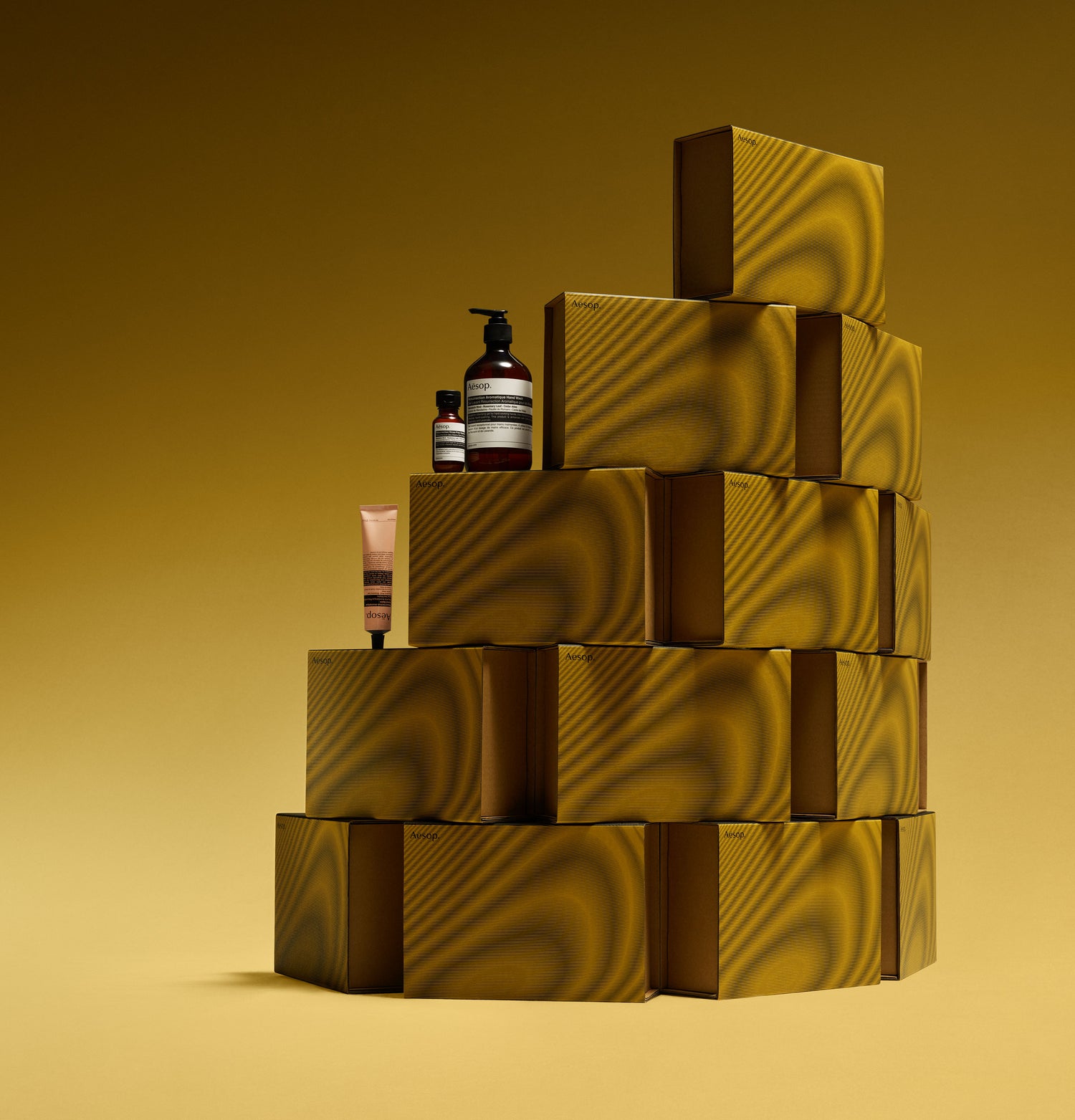 Aesop Tuneful Textures hand balm, hand wash & rinse-free hand wash placed on a stack of boxes.