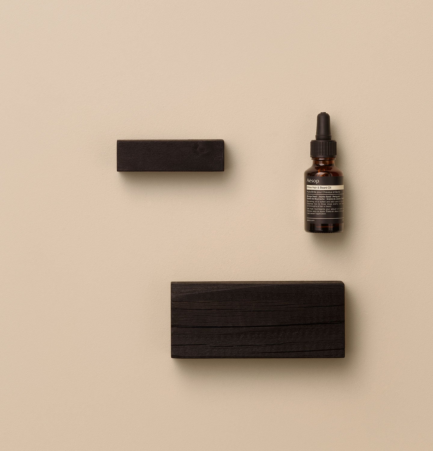 25ml bottle of Aesop Shine hair & beard oil placed by blocks